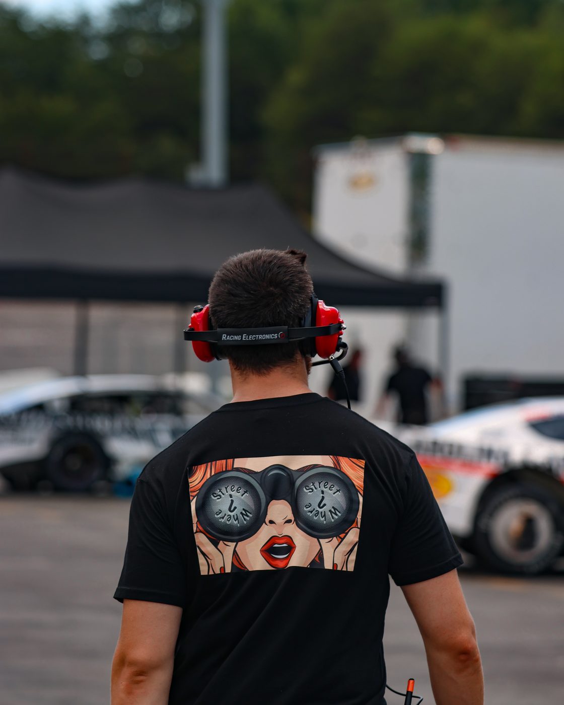 Crew member in the pits wearing a JC Racing shirt with the goggles graphic on the back